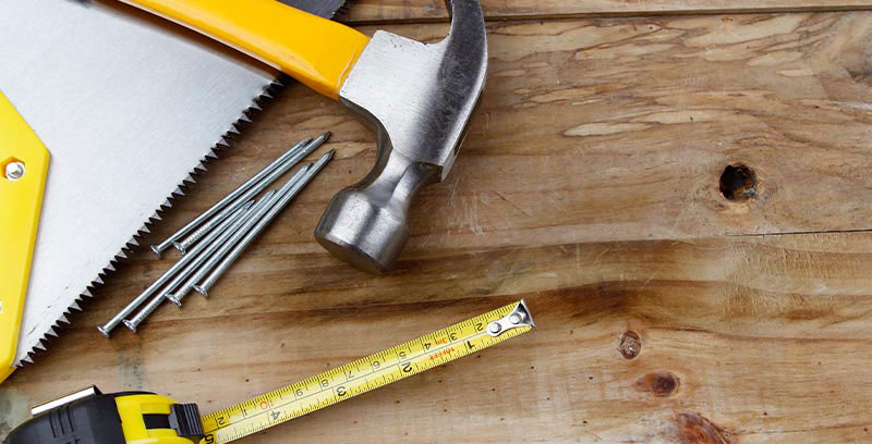 Hammer, saw, nail and measuring tape on a table