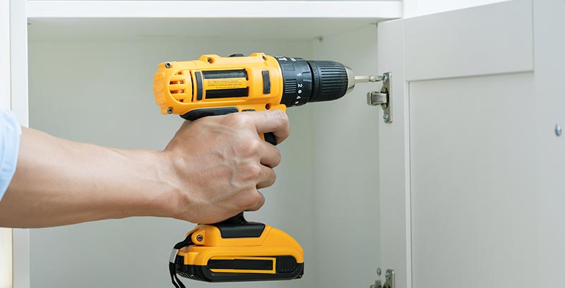 Cordless drill screwing a cabinet door